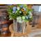 The side of a wood moose box holding a wildflower arrangement. It is decorating an entryway table. 
